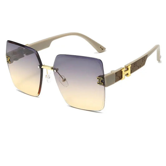Aethel oversized square sunglasses in light grey with gradient grey-to-yellow lenses and gold-tone H logo accents on the temples. Features a rimless design and UV400 protection.