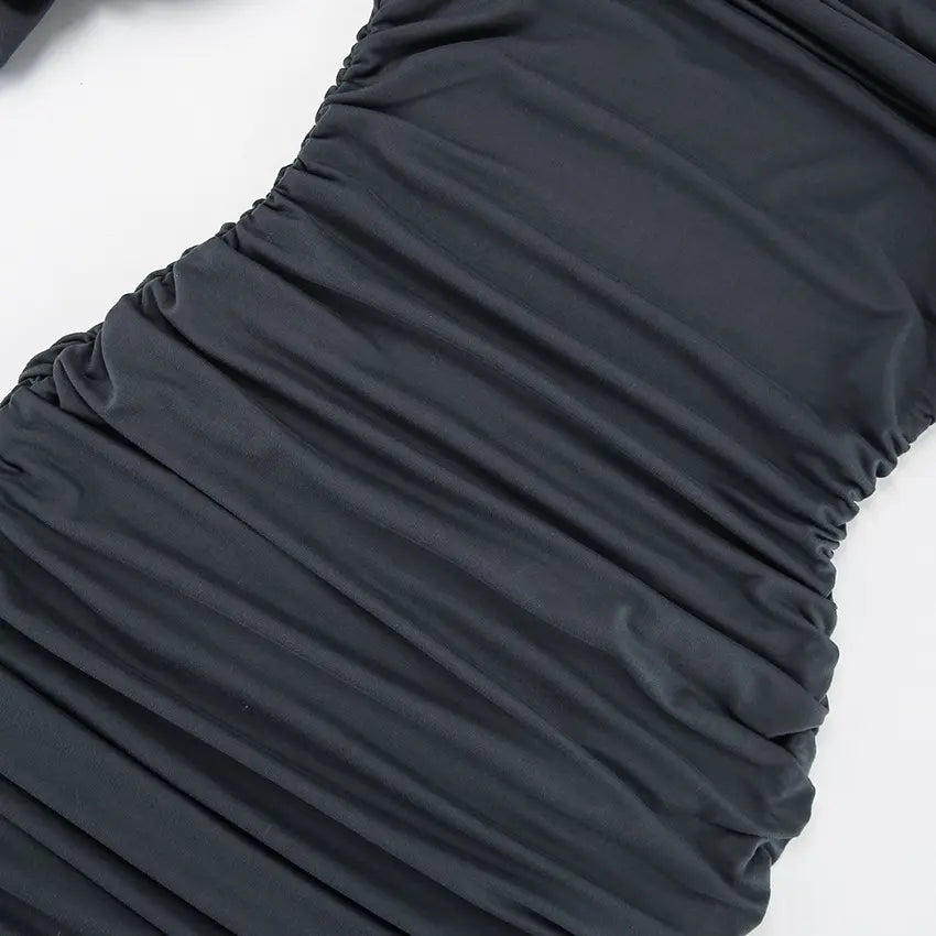 Close-up of a charcoal grey evening dress fabric showcasing intricate all-over asymmetrical ruching and draped texture.
