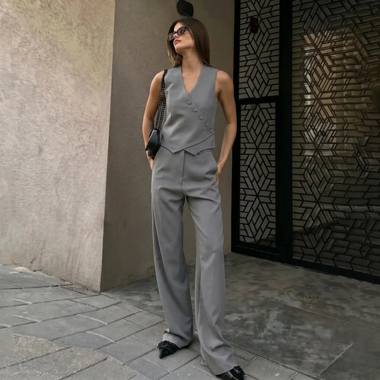 Model wearing a chic grey linen-blend vest and wide-leg trousers set, featuring an asymmetrical button-front vest and high-rise trousers, styled in an outdoor urban setting.
