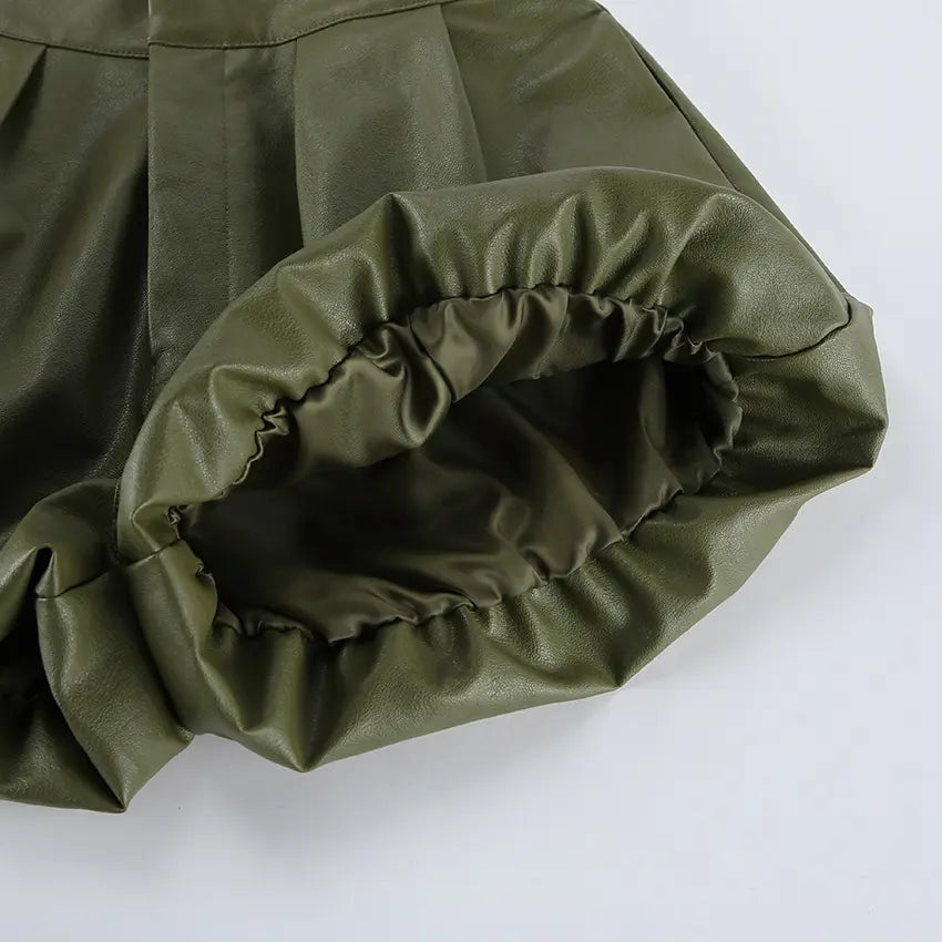 Close-up detail of olive green high-waist faux leather shorts, showcasing the gathered elasticated hem and subtle sheen of the material.