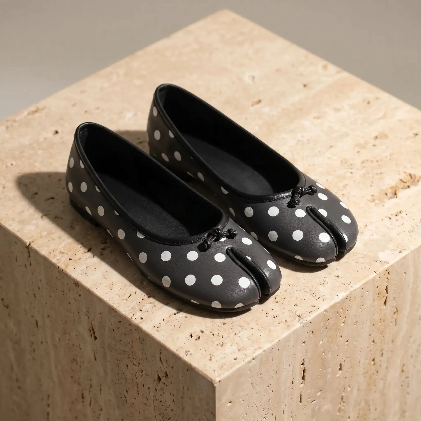 Lurran Polka Dot Noir split-toe vegan leather ballet flats with white polka dots and delicate bows, shown from a three-quarter angle.