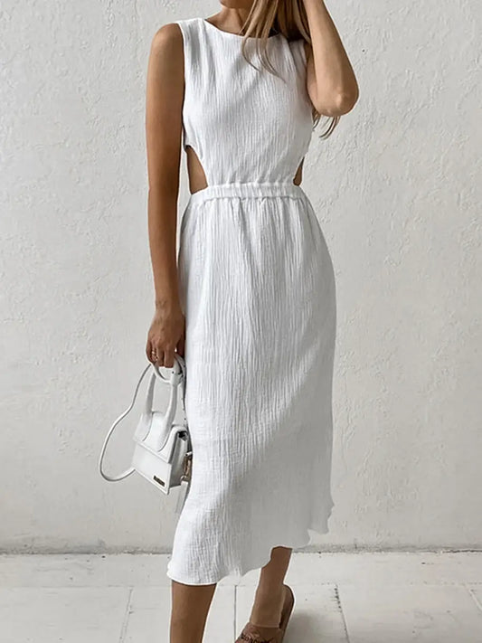 A white sleeveless midi dress with distinctive waist cut-outs and a crinkled bubble crepe texture is showcased on a model against a subtly textured wall.