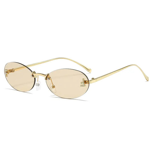 Elegant oval rimless sunglasses with a polished gold metal frame, featuring light amber gradient lenses and subtle jeweled letter embellishments on the temples.