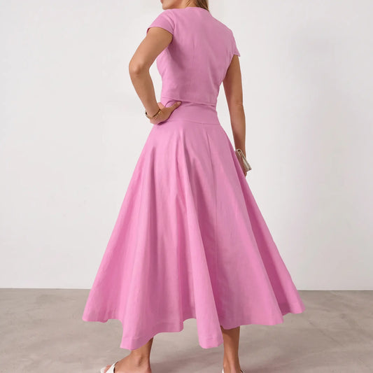 Elegant pink cotton two-piece set, featuring a cropped cap-sleeve top and a voluminous A-line midi skirt with a full button-front closure, shown from the back.