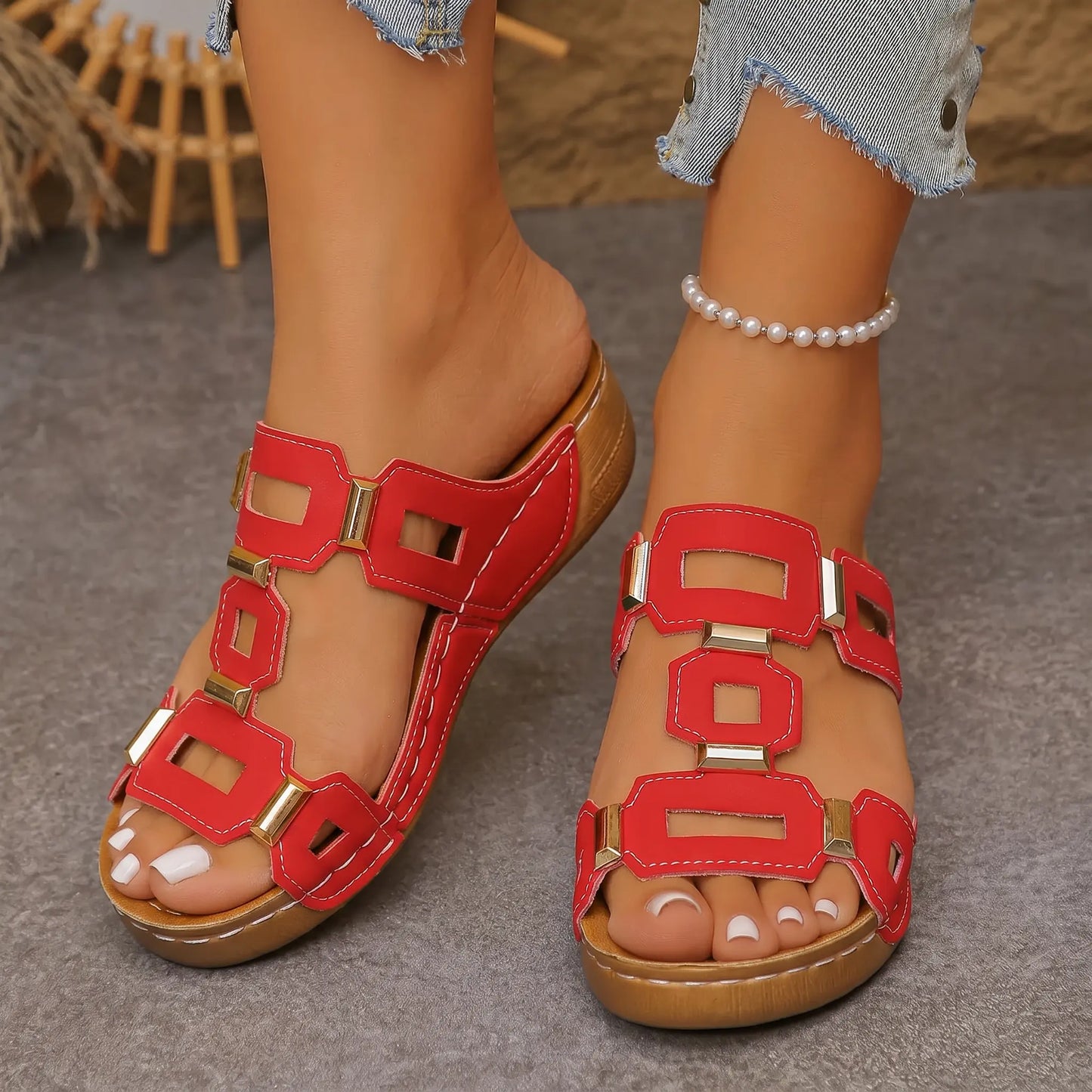Fiery red Kyorin platform wedge sandals with geometric gold embellishments and a T-strap design, worn by a model with a pearl anklet.