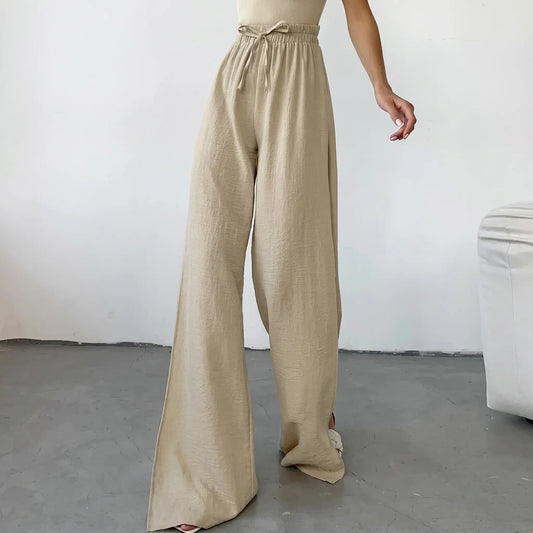 High-waisted, wide-leg trousers in textured oat-beige breathable cotton, featuring a drawstring waist and dramatic deep side slits up to the thigh.