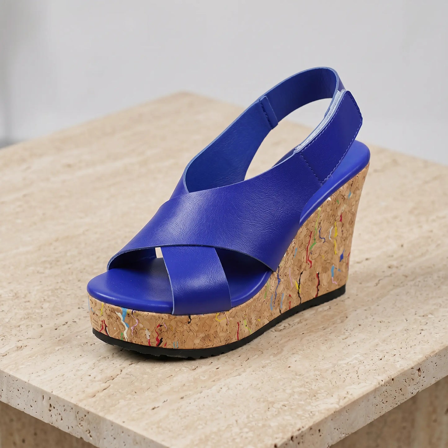 Royal blue women's platform wedge sandal with criss-cross faux leather straps and a cork-effect sole speckled with multi-colour flecks.