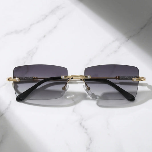 Vorali rimless square sunglasses featuring a gold-tone metal frame with crystal-embellished temples and gradient dark grey tinted lenses.