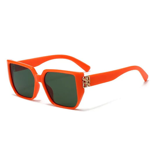 Vyrza oversized square sunglasses in vibrant orange acetate with gold-tone geometric temple detail and dark green tinted lenses.