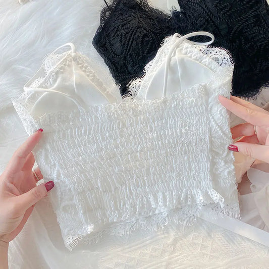 White Zyrin floral lace cropped camisole, highlighting its smocked back panel and delicate eyelash trim. A black camisole variant is partially shown.