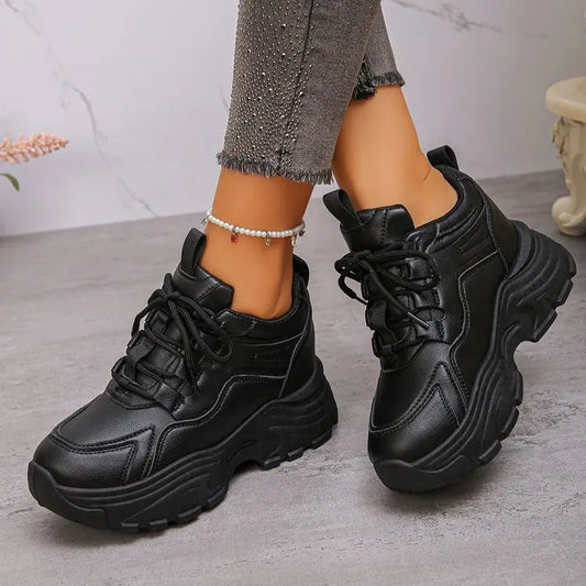 Black Zelpha chunky platform sneakers crafted from synthetic leather, showcasing a lace-up front and lugged sole, worn with embellished jeans and an anklet.