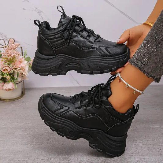 Zelpha black chunky platform sneakers styled on feet with embellished grey denim jeans and a pearl anklet, showcasing the smooth synthetic leather upper and lugged sole.