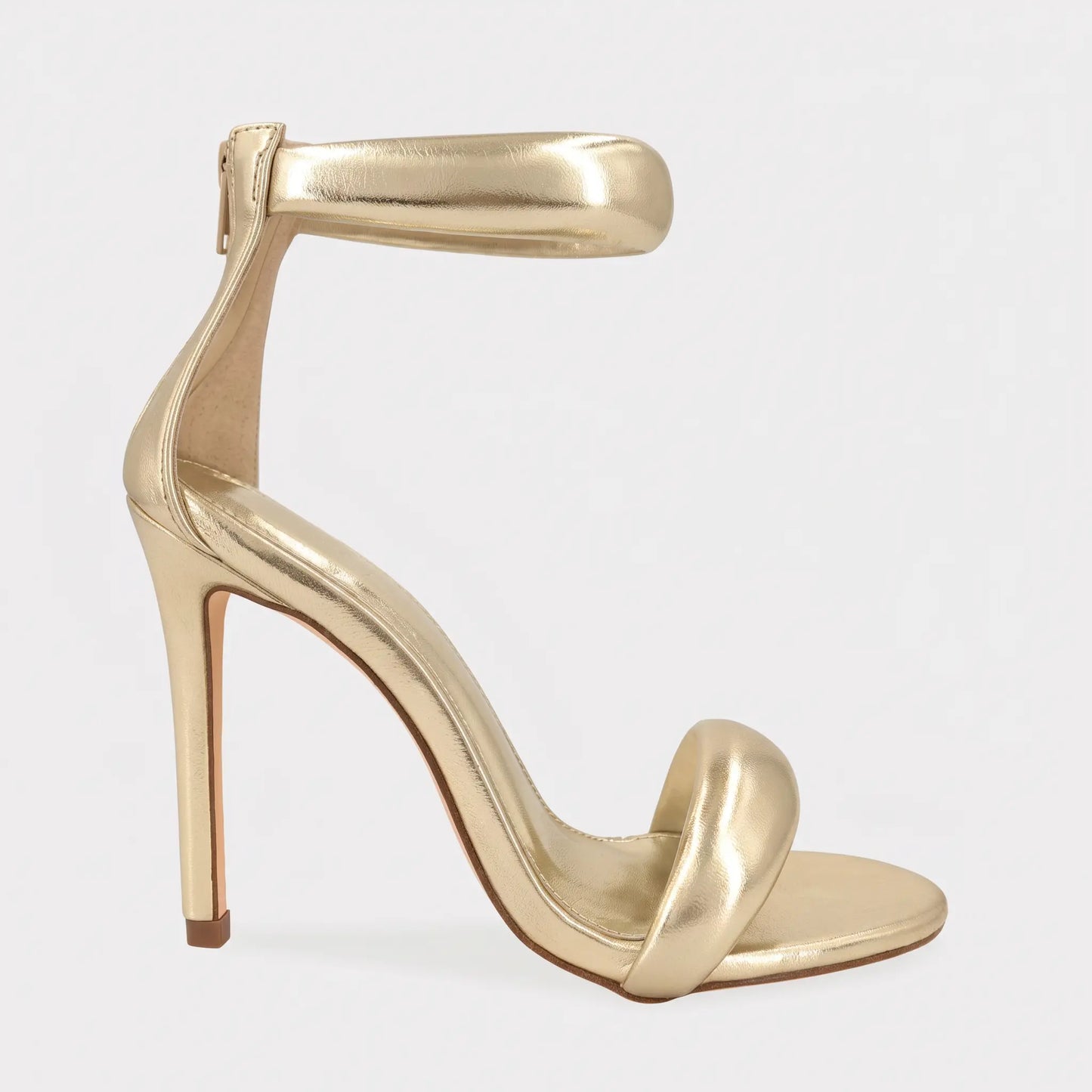 Zoltra elegant stiletto sandal in lustrous gold metallic finish, featuring a pointed toe, puffy toe strap, and wide puffy ankle strap with back zipper.