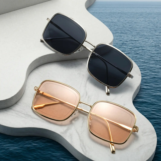 Two pairs of Zyphra square metal frame sunglasses, one gold with rose tint lenses and one silver with dark grey lenses, displayed on a studio background.