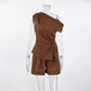 Aeloria chocolate brown linen-blend women's two-piece set featuring an asymmetrical draped top with a gold buckle accent and high-waisted shorts, displayed on a mannequin.