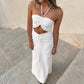 Aelyra white ruched halterneck maxi dress with midriff cut-out and drawstring waist, worn by a model on outdoor stairs.