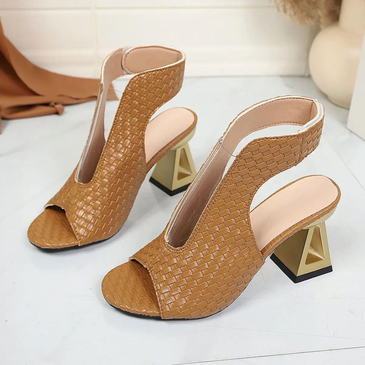 Aethel women's peep-toe block heel sandals in rich brown, featuring intricate woven texture and a metallic chain ankle strap shown from a three-quarter angle.