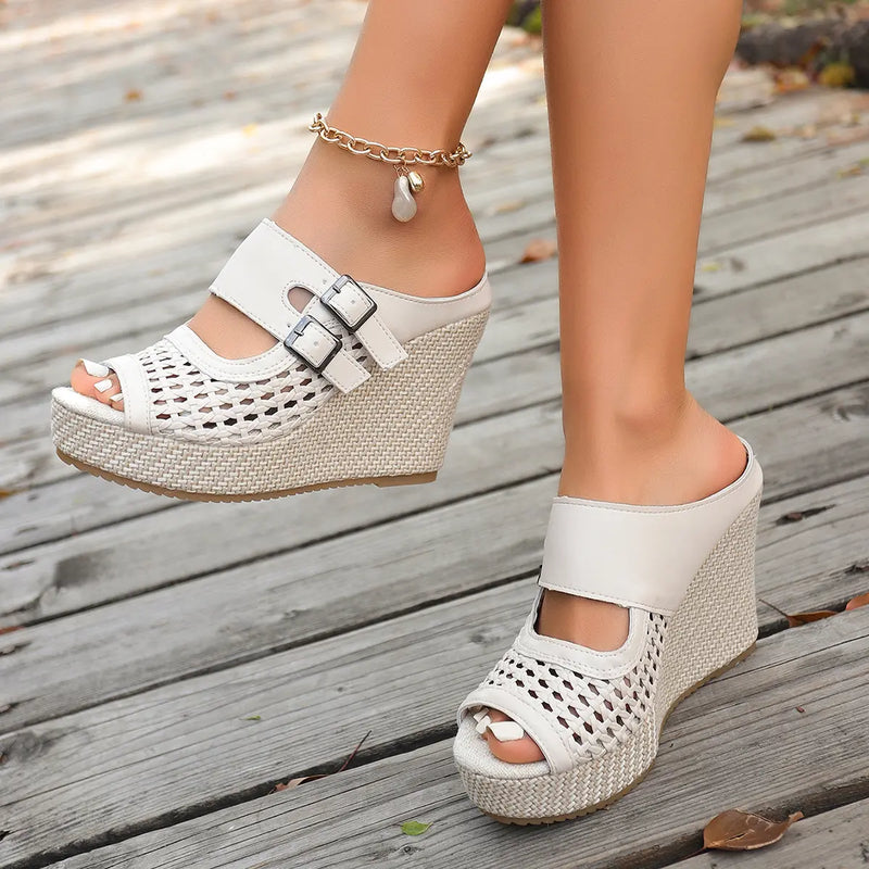 Cream Aethel woven wedge sandals with peep toe and dual buckle straps, elegantly worn on a wooden deck, showcasing their bohemian chic summer style.