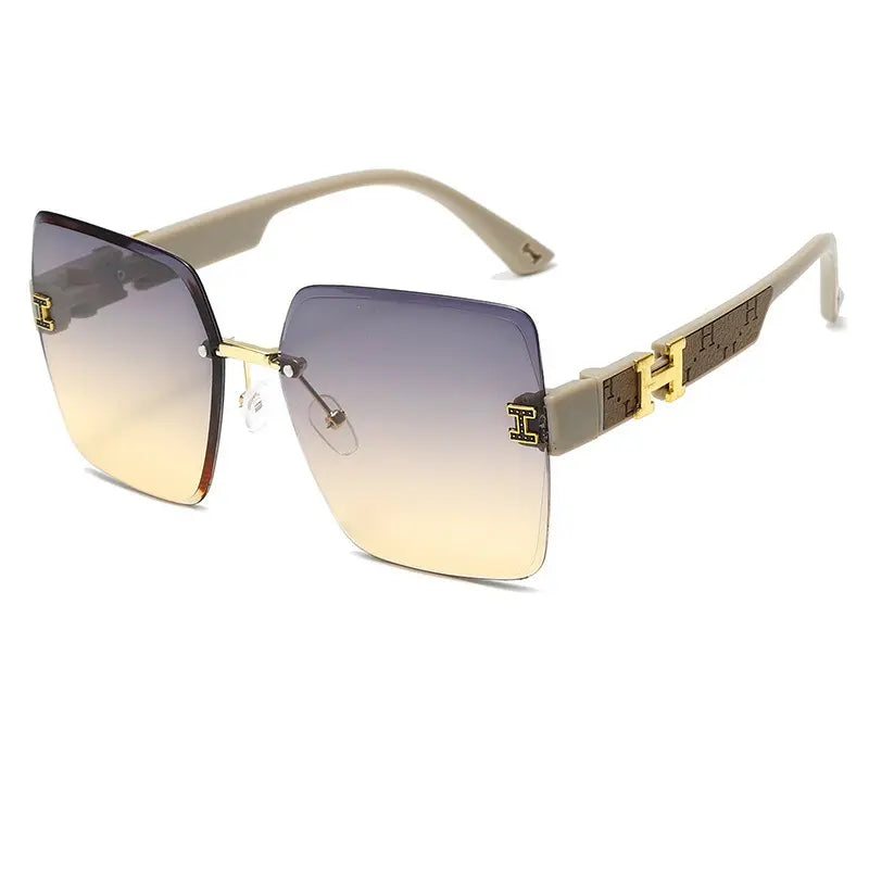 Aethel oversized square sunglasses in light grey with gradient grey-to-yellow lenses and gold-tone H logo accents on the temples. Features a rimless design and UV400 protection.