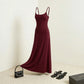 Aethel sleek maxi dress in deep burgundy with adjustable spaghetti straps, styled with a handbag and sandals in a minimalist room.
