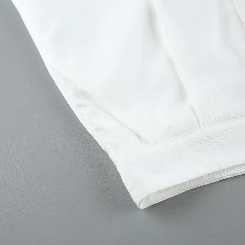 Close-up view of the off-white viscose blend fabric showing fine stitching, crisp pleats, and a side pocket detail on a pair of trousers.