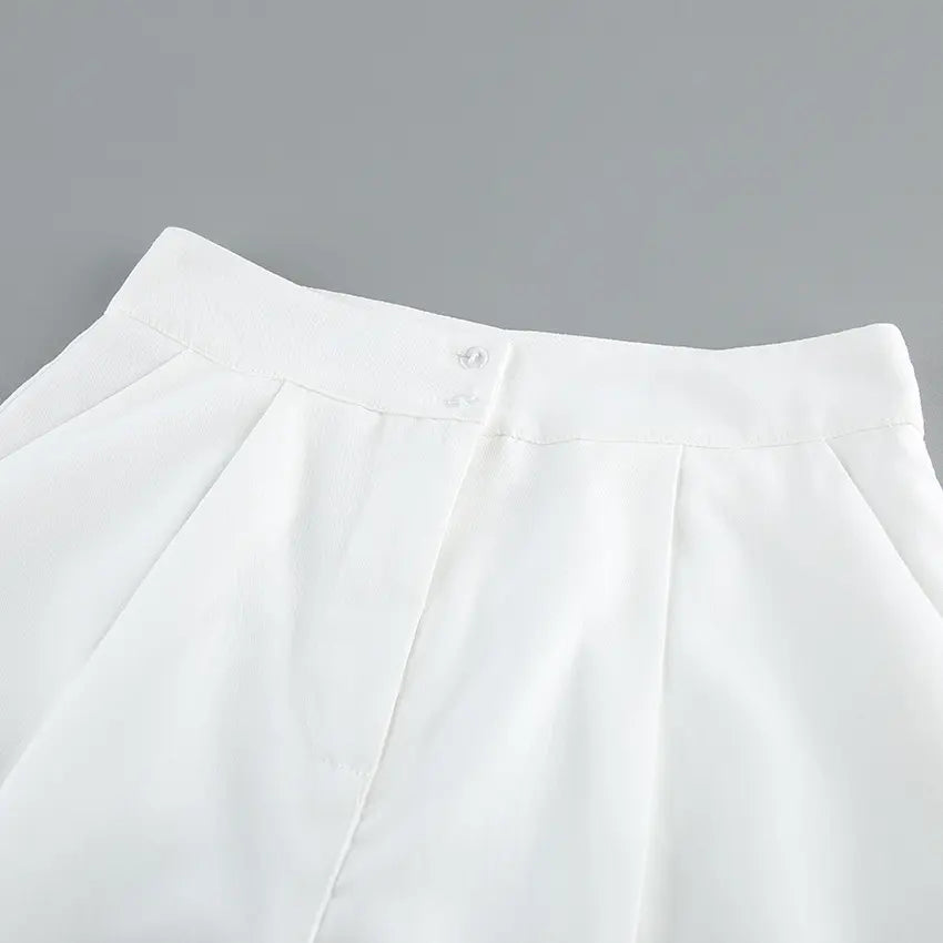 Close-up view of the waistband on off-white wide-leg trousers, showcasing crisp pleats, a single button, and textured fabric detail.