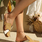 Aevana bohemian flat slides with oversized leaf embellishments and crystal-adorned block heels worn on a woman's feet, styled with a subtle anklet in an outdoor setting.