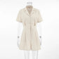 Azkari oat-beige linen-blend jumpsuit featuring a camp collar, short sleeves, button-down front, and wide-leg shorts, shown on a mannequin against a white studio background.