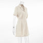 Azkari oat beige linen-blend short-sleeve jumpsuit with camp collar and wide-leg shorts, presented from a side view on a clear mannequin.