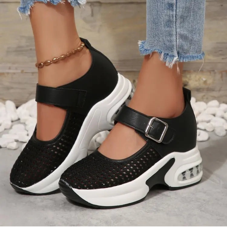 Baxar women's black breathable mesh platform sneakers with a white sculpted sole, silver buckle strap, and visible air cushion heel, shown on feet with distressed jeans.