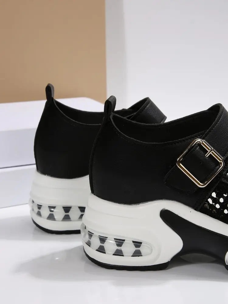 Close-up side view of black women's platform sneakers featuring a white sculpted sole with a visible translucent air cushion heel and a buckled strap.