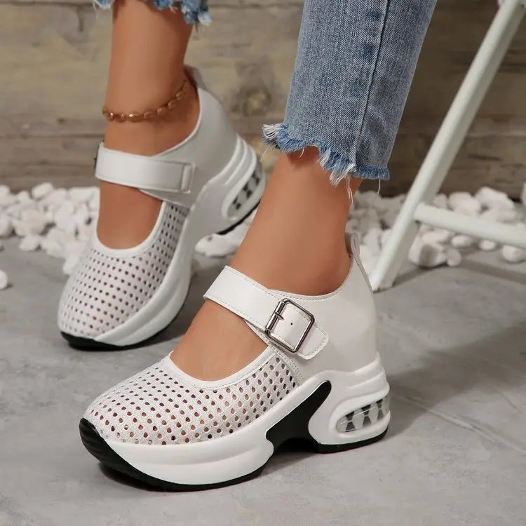 Women's white breathable mesh sneakers with a silver buckle strap closure and a translucent air cushion heel, shown on a person wearing ripped jeans.