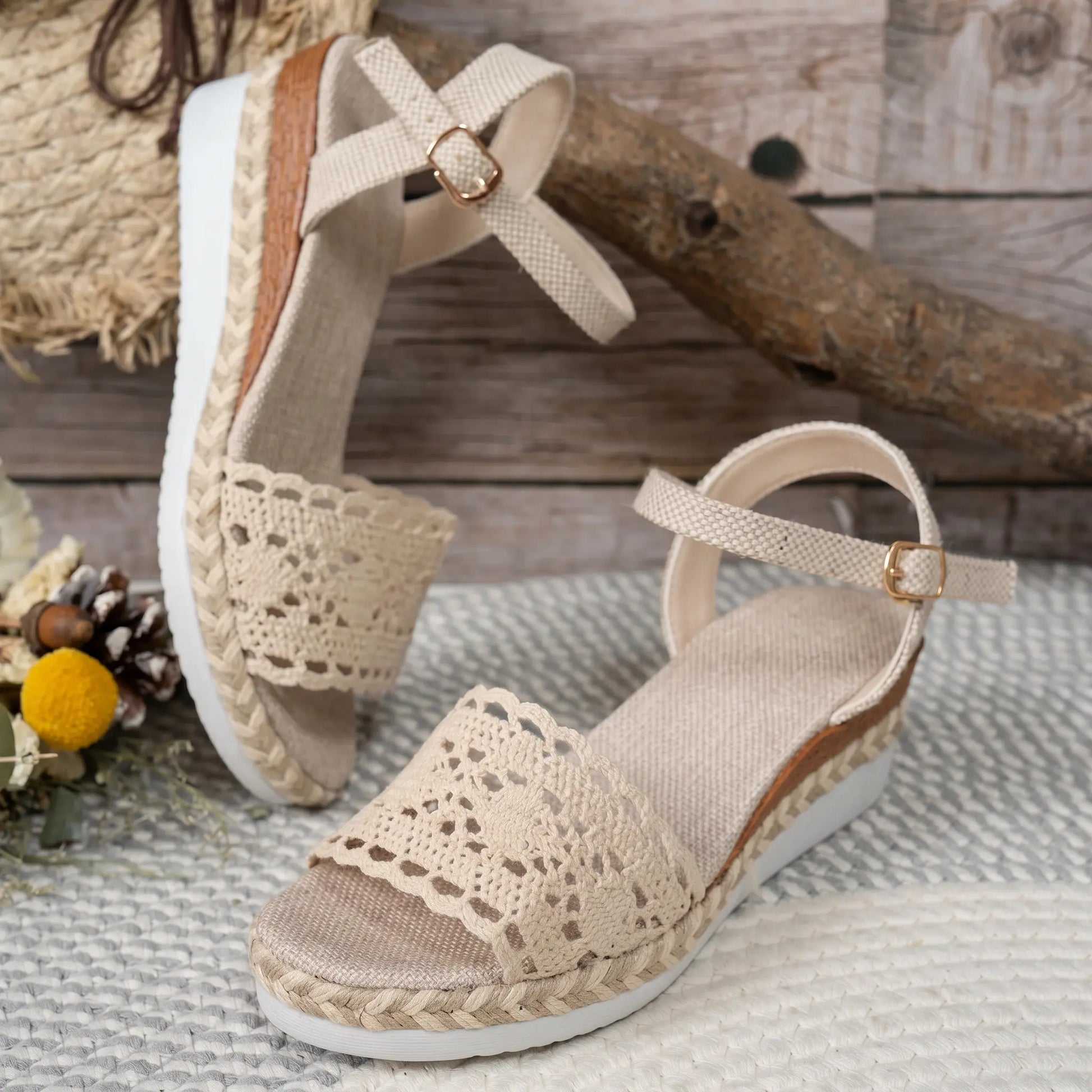Kryphos women's beige espadrille wedge sandals featuring intricate crochet lace detailing on the vamp and an adjustable ankle strap with a gold-tone buckle, presented in a charming lifestyle setting.
