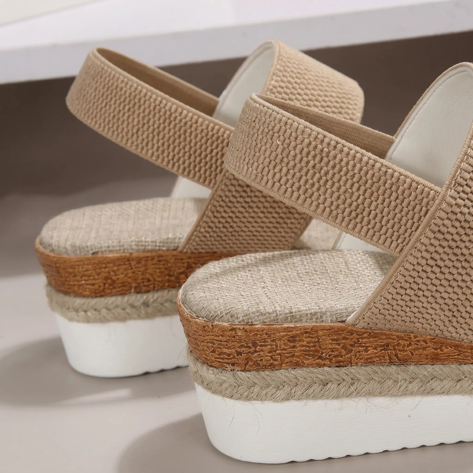 Close-up side view of beige woven fabric espadrille wedge sandals showcasing the natural jute rope wrap on the platform sole and mid-height wedge heel.