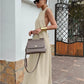 Woman wearing a flowing beige halter neck maxi dress with a tie-back, accessorized with sunglasses and a handbag, styled for a chic resort look.