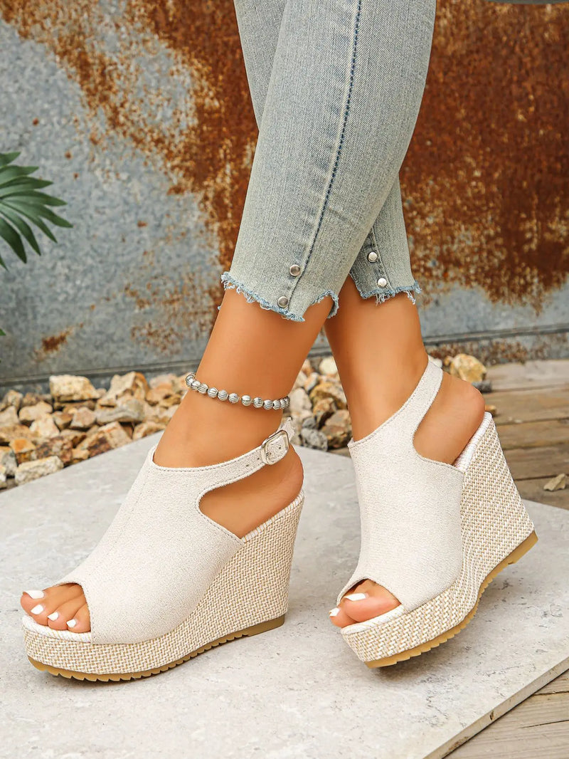 Earthy beige peep-toe espadrille wedge sandals with a jute-wrapped heel and ankle strap, worn with distressed denim jeans.