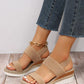 Women's beige woven espadrille wedge sandals with a fish-mouth open toe and elasticated slingback strap, styled with denim jeans on a wooden floor.