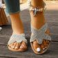 Close-up lifestyle view of embellished starfish flat sandals worn on feet with a seashell anklet, showcasing crystal-covered straps and a light tan footbed against a wooden deck.
