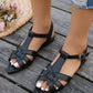 Black bohemian flat sandals with a pointed toe, featuring delicate woven straps and an elasticated slingback heel, shown on feet styled with denim jeans on a wooden deck.