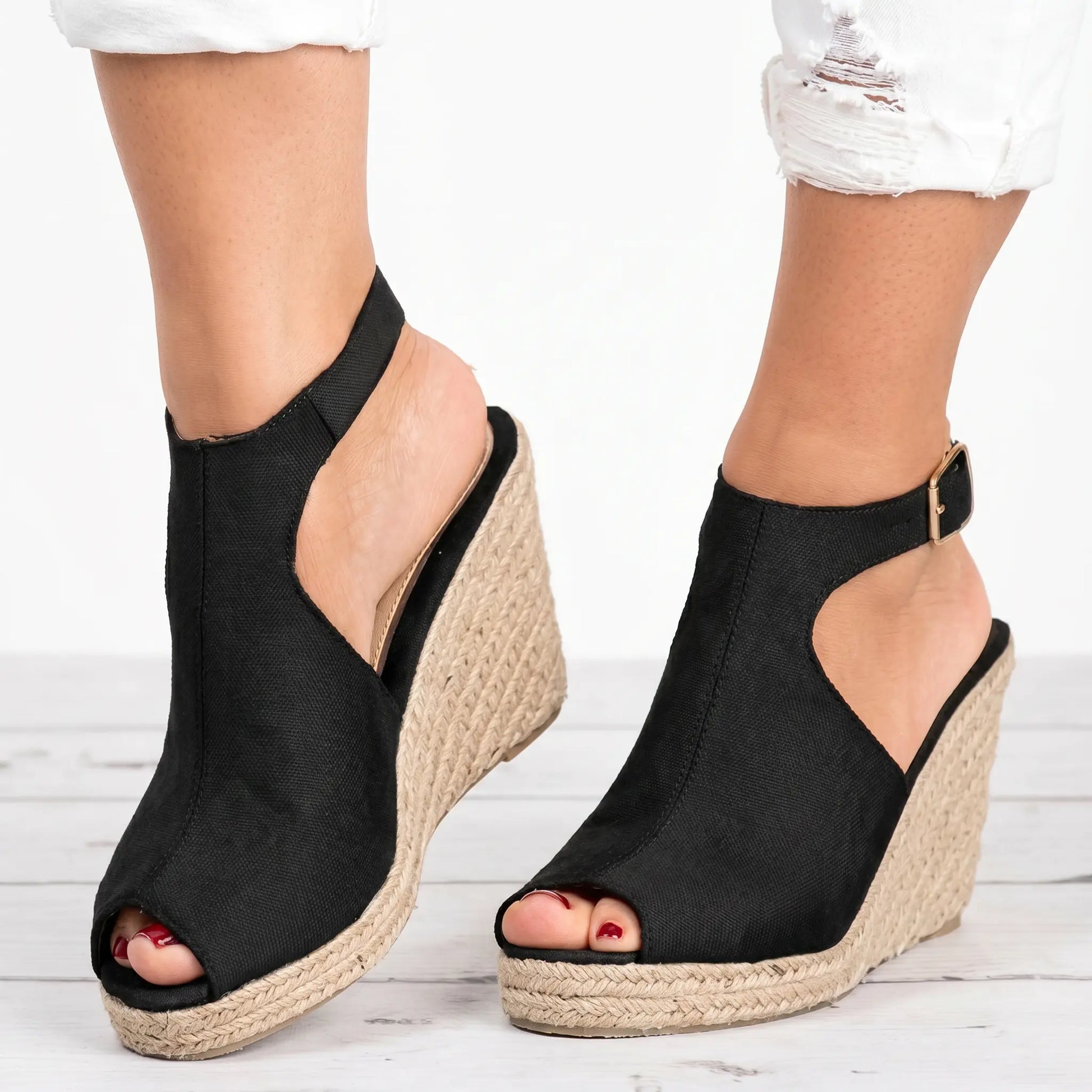 Black espadrille wedge sandals with a peep-toe front, adjustable gold-tone ankle strap, and a natural jute woven sole, shown from a three-quarter angle.
