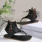 Black PU leather flat gladiator sandals with thong toe, lace-up ankle straps, and white contrast stitching around the sole.