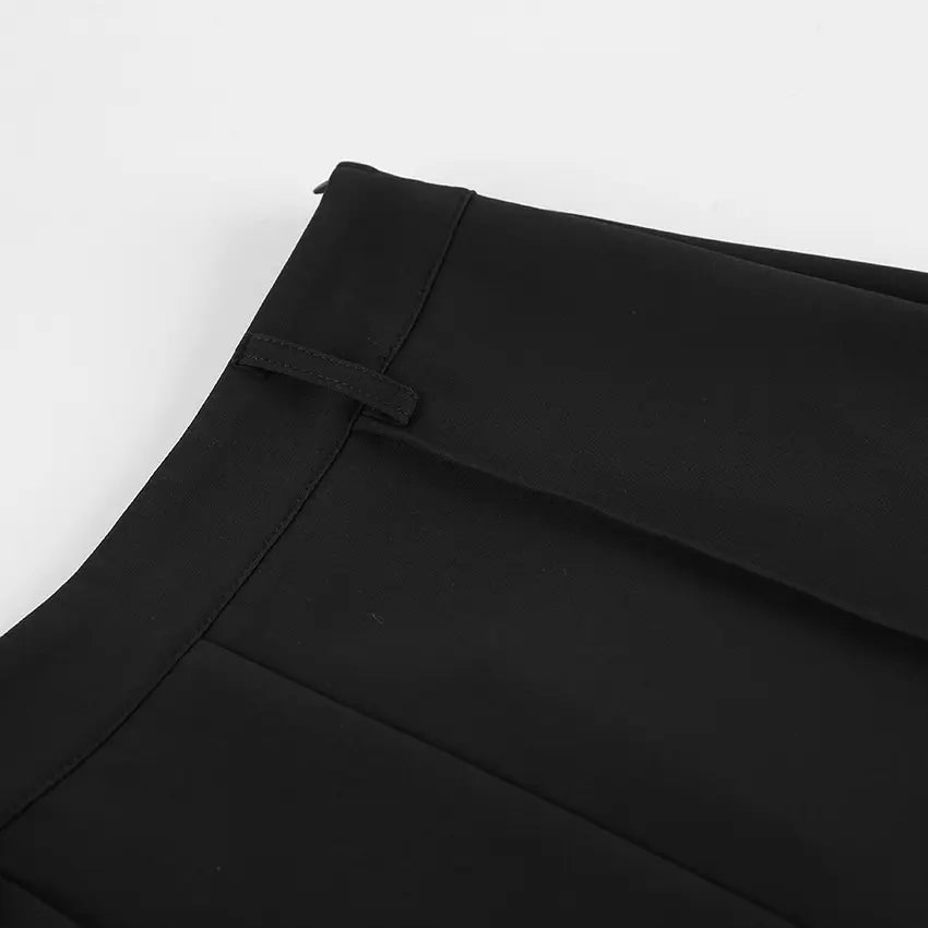 Close-up view of black high-waisted tailored shorts, showcasing the structured waistband, crisp front pleats, and a discreet side zipper closure detail. A refined shot highlighting the garment's construction.