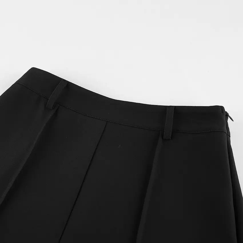Close-up view of black tailored high-waisted shorts, showcasing the flat waistband, front pleats, and side zipper detail.