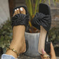 A pair of women's black slip-on slide sandals with a square toe and a textured knot detail on a single wide strap, shown on a foot with white nail polish and a gold bracelet. The sandal features a low block heel and the brand name 'Shilanna' is visible on the sole.