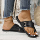 Elegant black leather flat sandals for women, featuring a toe-thong design, crisscross straps, and an adjustable buckle, shown with frayed denim jeans.