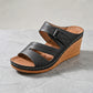 Black Zephira women's wedge sandal with peep-toe, laser-cut floral perforations, adjustable hook-and-loop strap, and white contrast stitching on a wood-grain wedge heel.