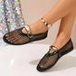 Black mesh flat sandals for women featuring patent trim, a decorative polished metallic oval buckle strap, and a beaded ankle bracelet, shown on a model's foot.