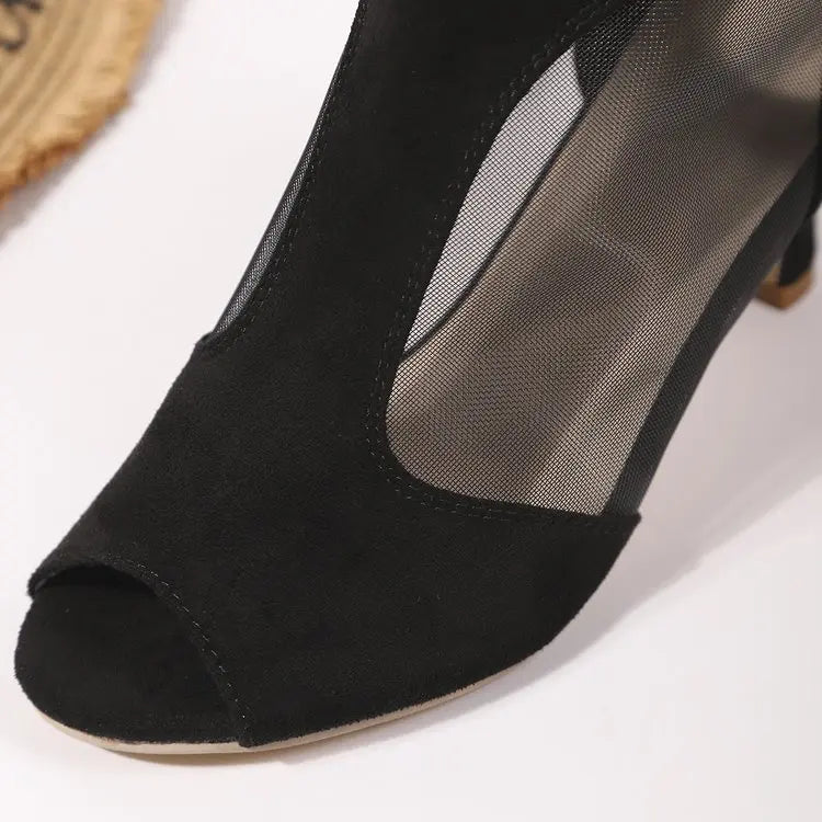 Close-up of black suede-like peep-toe ankle boots featuring sheer mesh side panels and a stiletto heel, highlighting texture and design details.