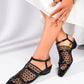 Pair of women's black mesh pointed-toe heeled sandals with intricate woven straps and a low block heel, shown on a model's feet against a white studio background.