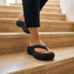 Black Mivon chunky platform thong sandals with wide straps and 5cm elevated EVA sole, worn by a person walking on light stone steps. Seamless matte finish.